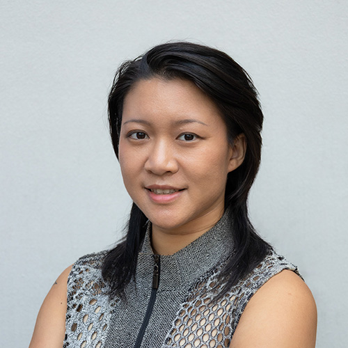 portrait of a smiling woman with shoulder-length black hair against a clean grey backdrop